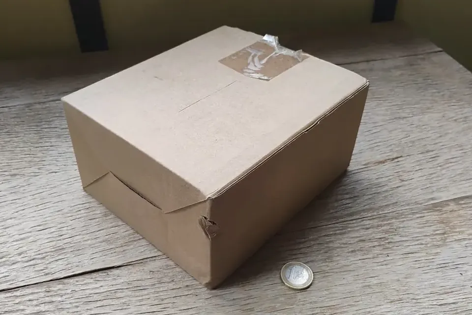 A plain taped cardboard box on a weathered wooden table