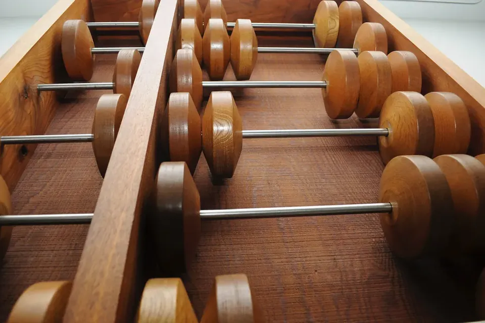 Large wooden beads on the metal rods of an oversized abacus, seen from below