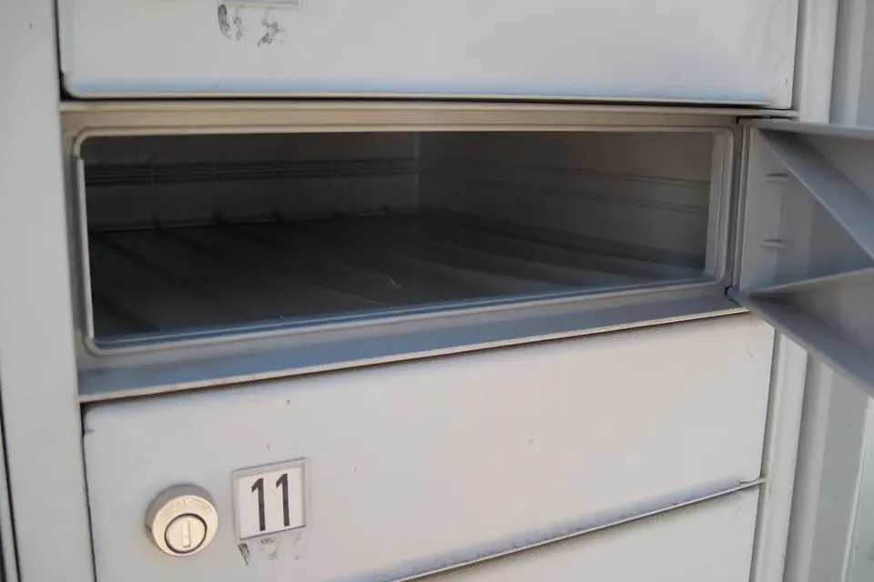 An open, empty metal mailbox compartment above a locked one numbered 11